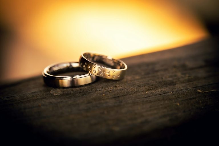 Deux alliances posées sur une table en bois, illustration du divorce et du partage des biens chez le notaire
